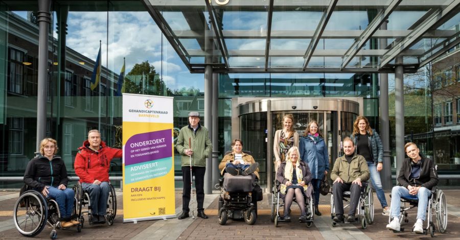 Leden van de Gehandicaptenraad en ambtenaren vóór het gemeentehuis Barneveld